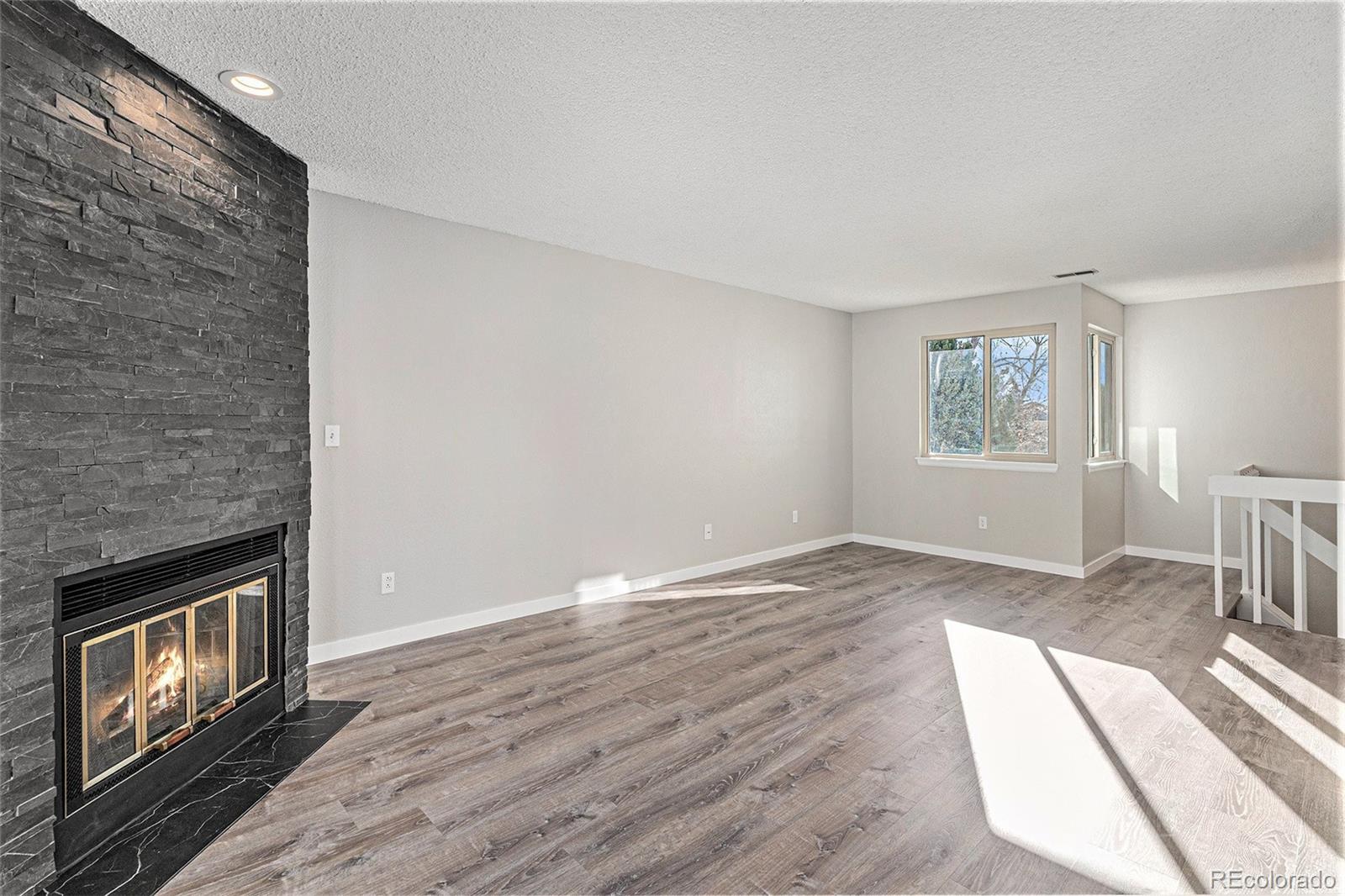8414 South Everett Way, Unit F Littleton, CO 80128 - Photo 6 of 13 an empty room with windows fireplace and wooden floor