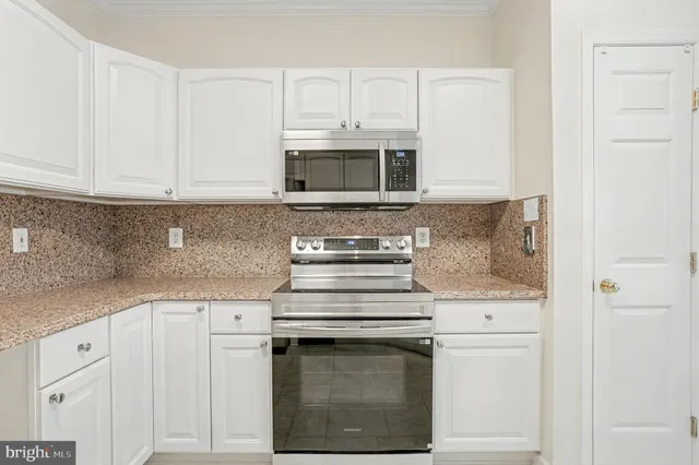 a kitchen with granite countertop white cabinets and white stove