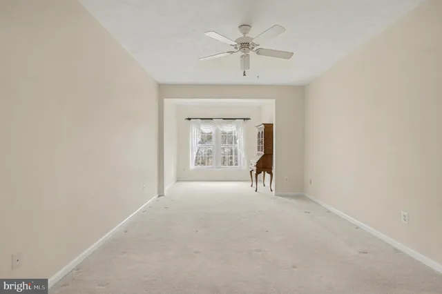 an empty room with a ceiling fan and a window