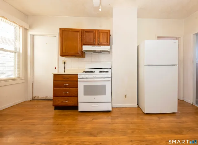 a view of an empty room with a kitchen and a window