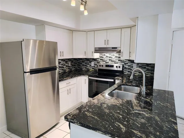 a kitchen with granite countertop a refrigerator stove and sink