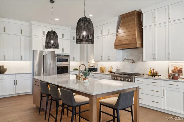 a kitchen with stainless steel appliances a sink a stove and chairs