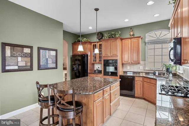 a kitchen with stainless steel appliances granite countertop a stove top oven a sink dishwasher and a refrigerator with wooden cabinets