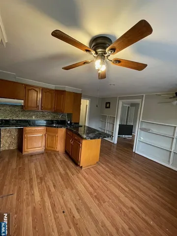 a kitchen with stainless steel appliances kitchen island granite countertop wooden floors and a sink