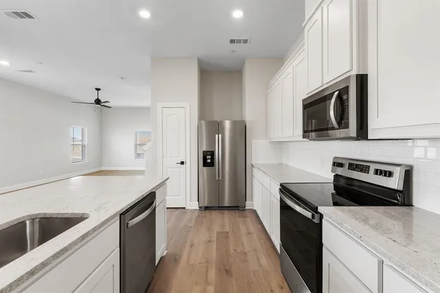 a kitchen with stainless steel appliances kitchen island granite countertop a stove a sink and a microwave