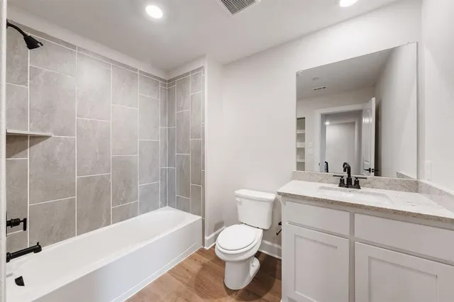 a bathroom with a bathtub shower sink vanity mirror and toilet