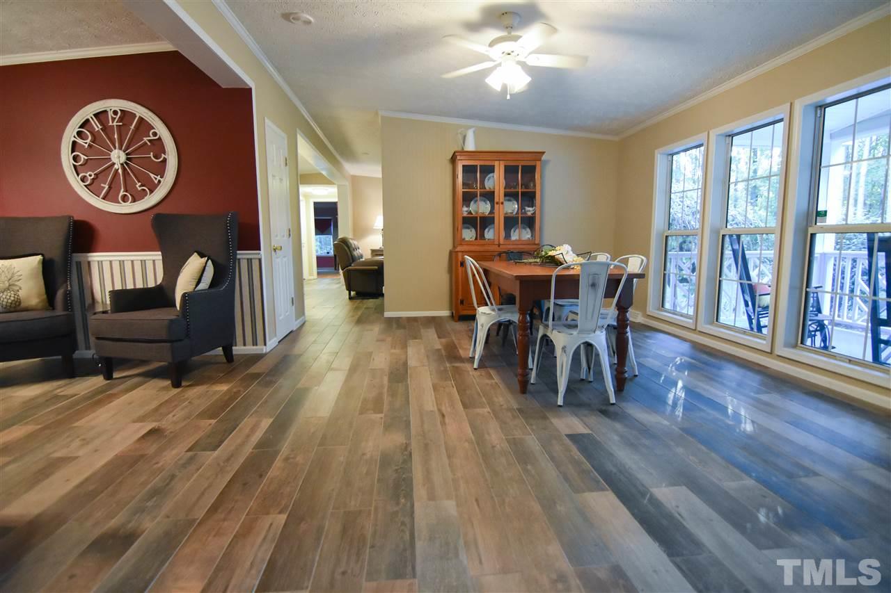 727 Ned Moore Road Timberlake, NC 27583 - Photo 10 of 24 a dining room with wooden floor a chandelier a wooden table and chairs