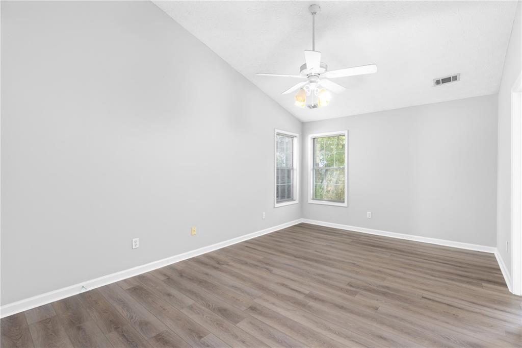 2110 Racquet Club Circle Northwest Lawrenceville, GA 30043 - Photo 20 of 44 an empty room with wooden floor chandelier fan and windows
