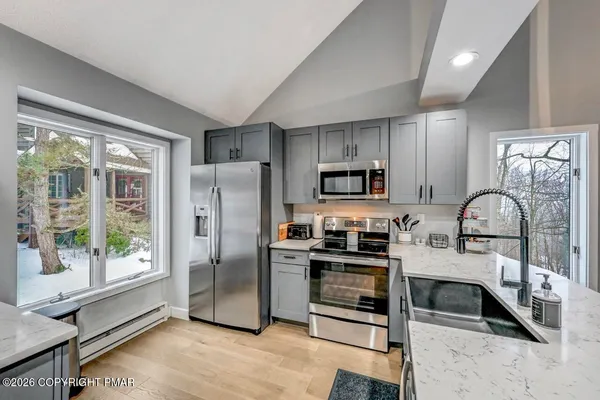 a kitchen with stainless steel appliances granite countertop a refrigerator a stove a sink and a granite counter tops with white cabinets