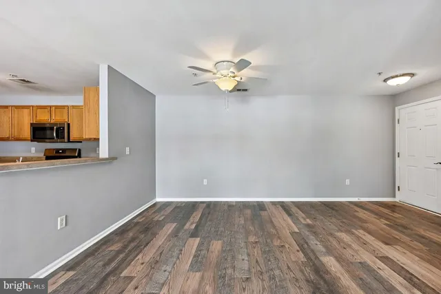 a view of a room with wooden floor and a ceiling fan