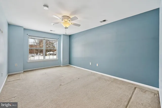 an empty room with windows and fan