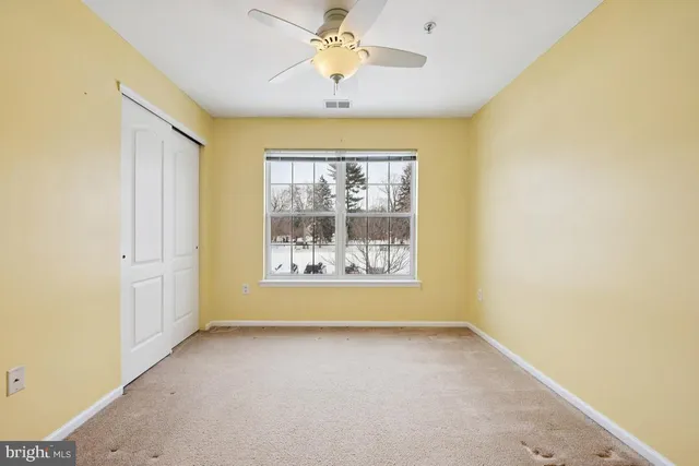 an empty room with a window and a chandelier fan