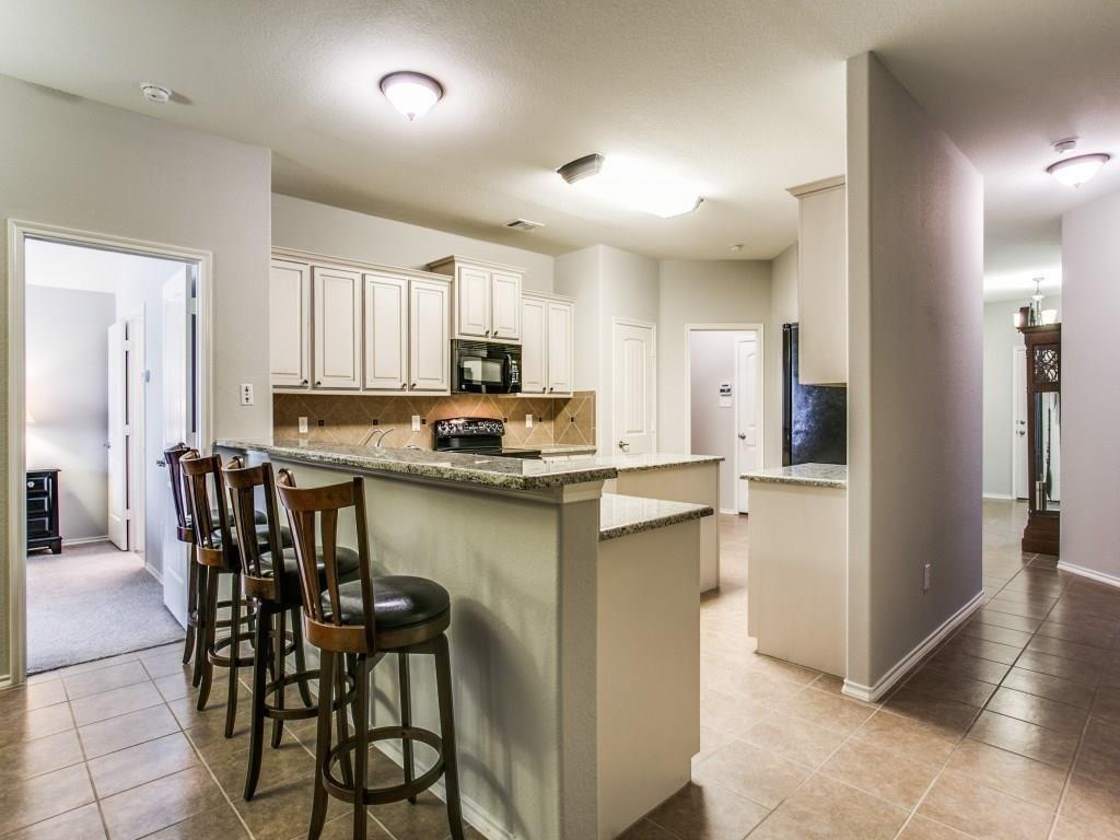 1097 Luton Drive Prosper, TX 75078 - Photo 12 of 25 a kitchen with kitchen island a dining table chairs refrigerator and cabinets