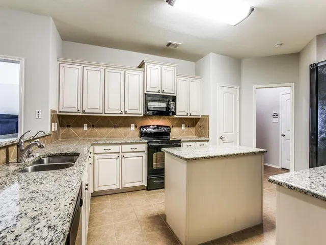 a kitchen with stainless steel appliances granite countertop a stove top oven a sink a refrigerator and white cabinets