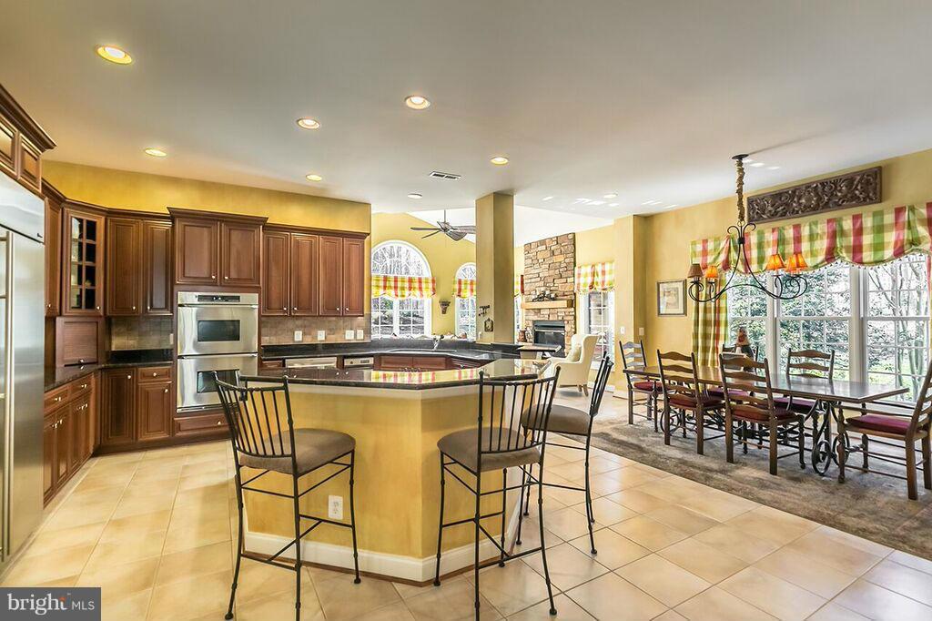 604 Clear Spring Road Great Falls, VA 22066 - Photo 7 of 28 a kitchen with stainless steel appliances a stove a refrigerator a kitchen island a stove and a dining table with wooden cabinets
