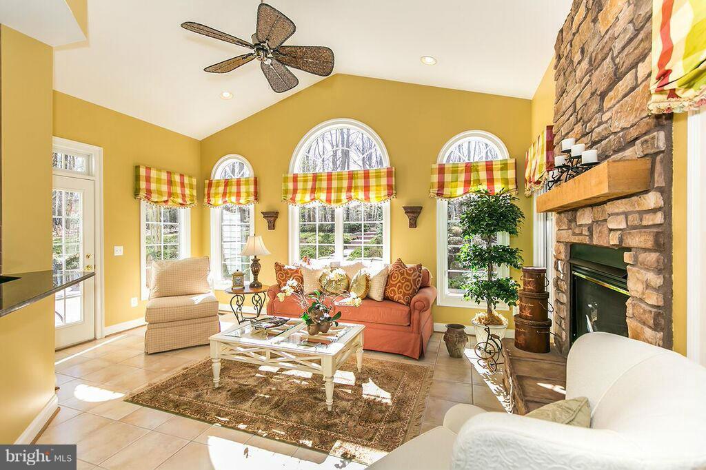604 Clear Spring Road Great Falls, VA 22066 - Photo 8 of 28 a living room with couches a fireplace and a dining table with wooden floor