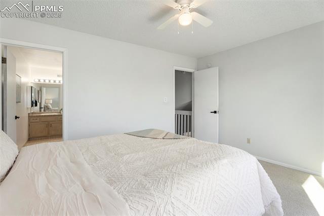 86 Rising Sun Terrace Colorado Springs, CO 80921 - Photo 20 of 36 Bedroom featuring light colored carpet, ensuite bath, a textured ceiling, and ceiling fan