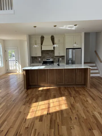 a large kitchen with wooden floors and stainless steel appliances