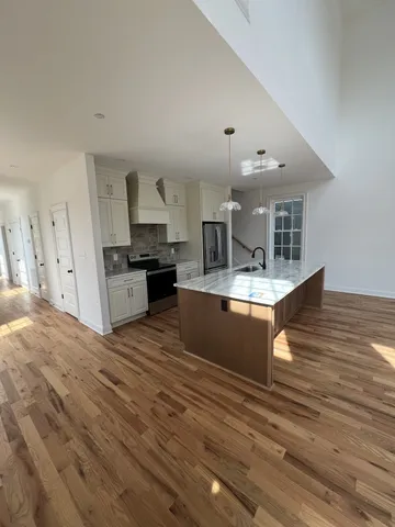 a large kitchen with stainless steel appliances granite countertop a stove and a wooden floors