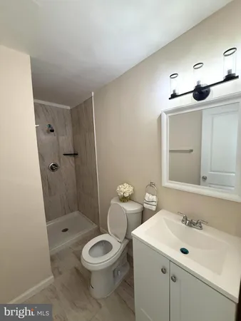a bathroom with a toilet a sink a mirror and shower