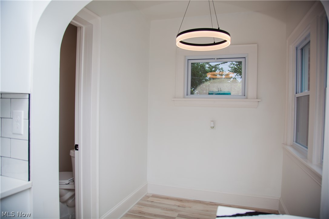 3554 Ludgate Road Shaker Heights, OH 44120 - Photo 18 of 50 Arched doorway, sleek circular pendant light fixture, multiple windows, wood-finish flooring, and white subway tile backsplash