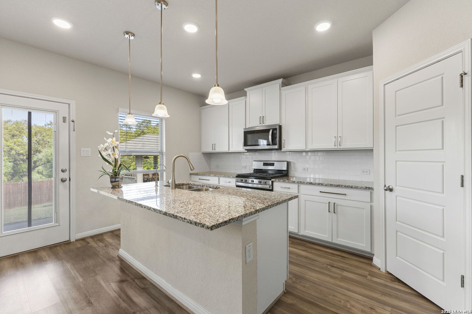12221 Icon Ridge San Antonio, TX 78253 - Photo 12 of 46 a kitchen with kitchen island granite countertop a sink cabinets and wooden floor