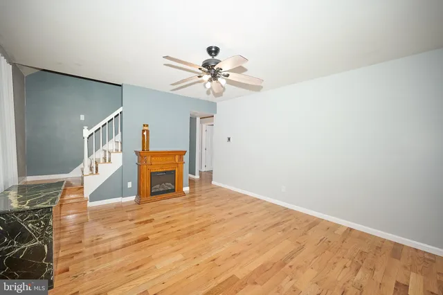 a view of an empty room with window and chandelier fan