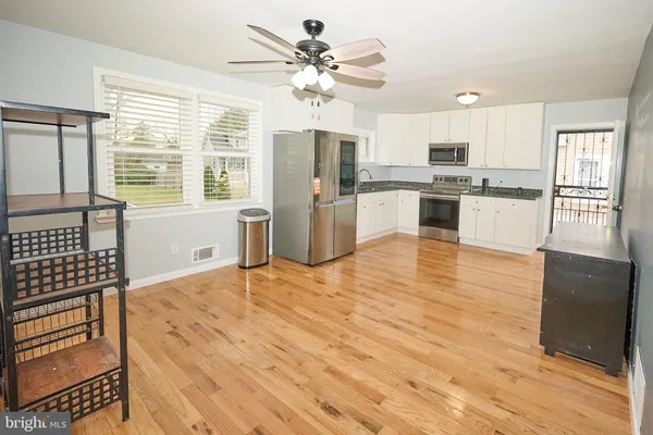 a large white kitchen with granite countertop a stove a sink dishwasher and a refrigerator with wooden floor