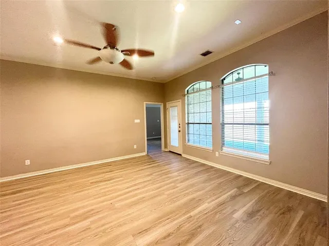 an empty room with wooden floor and windows