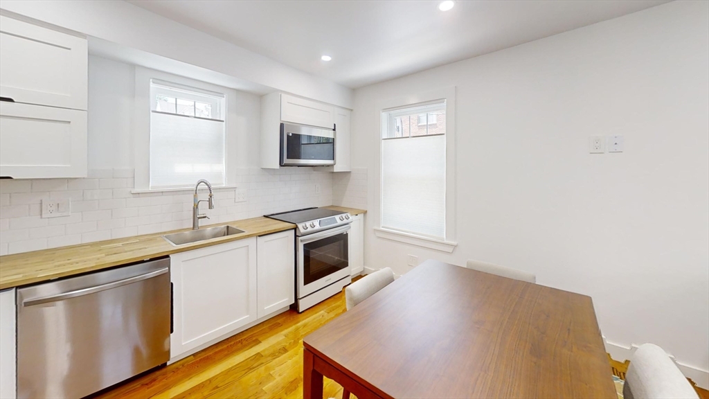 36 Shepard Street, Unit 1 Boston, MA 02135 - Photo 24 of 29 a kitchen with stainless steel appliances a sink cabinets and a wooden floor