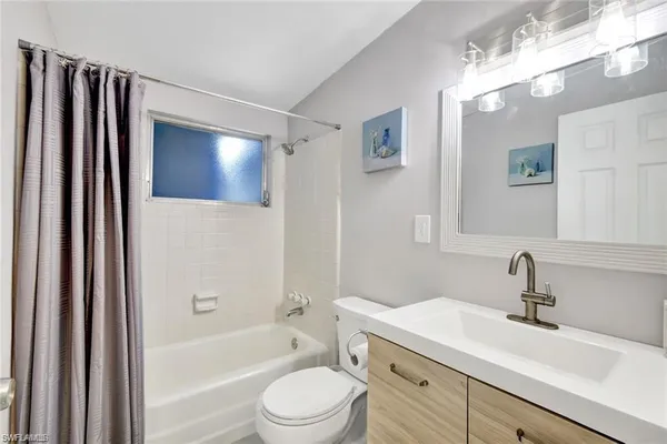 a bathroom with a sink a toilet a mirror a vanity and bathtub