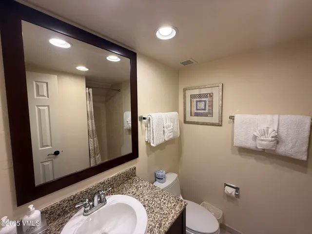 a bathroom with a granite countertop sink mirror vanity and toilet