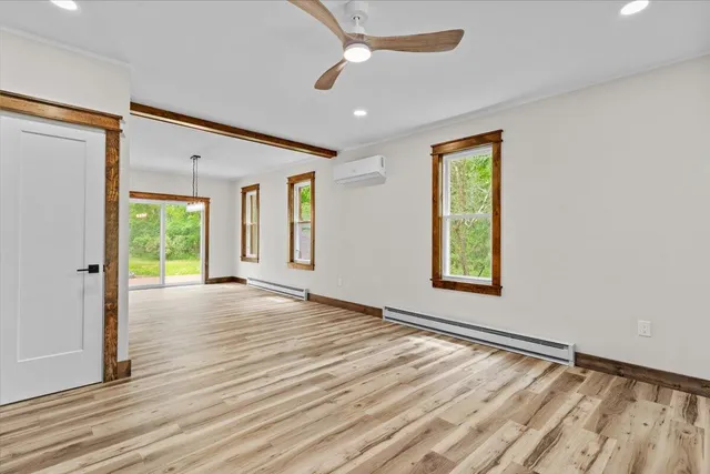 a view of an empty room with a window and wooden floor