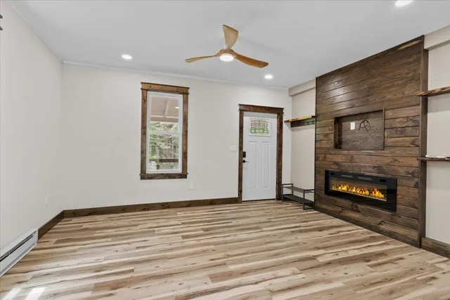 a view of an empty room with wooden floor fireplace and a window