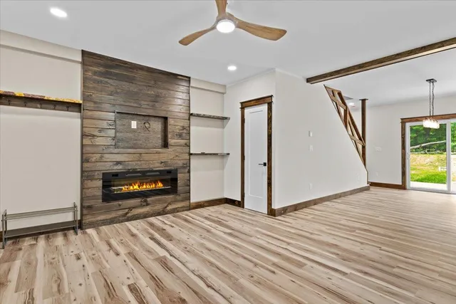 a view of an empty room with wooden floor fireplace and a window