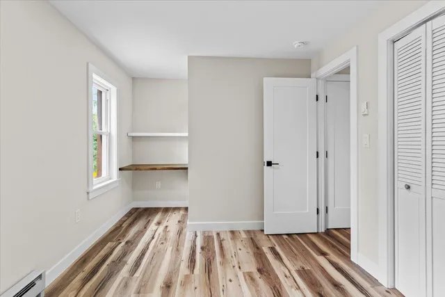 a view of empty room with wooden floor and fan