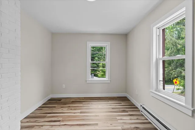a view of an empty room with wooden floor and a window