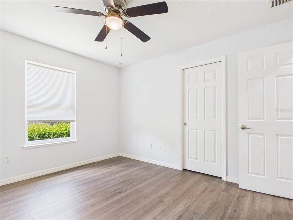 4309 Southwest 143rd Ln Road Ocala, FL 34473 - Photo 13 of 21 an empty room with wooden floor ceiling fan and windows