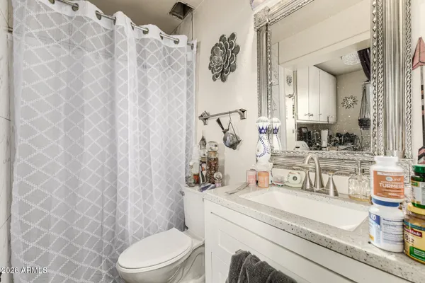 a bathroom with a granite countertop sink mirror vanity and toilet