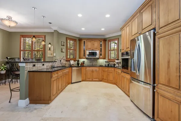 a large kitchen with stainless steel appliances granite countertop a refrigerator a sink a stove and a refrigerator