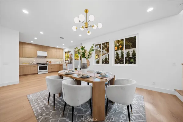 a dining room with wooden floor a chandelier a wooden table and chairs