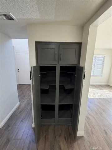 a view of an empty room with wooden floor and closet