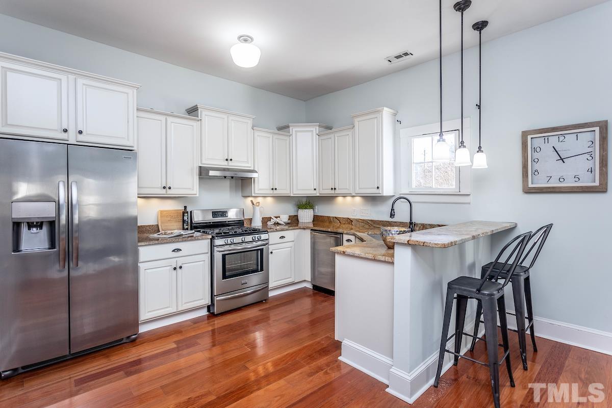 529 East Martin Street Raleigh, NC 27601 - Photo 11 of 29 a kitchen with stainless steel appliances granite countertop white cabinets a sink a stove a refrigerator and island with wooden floor
