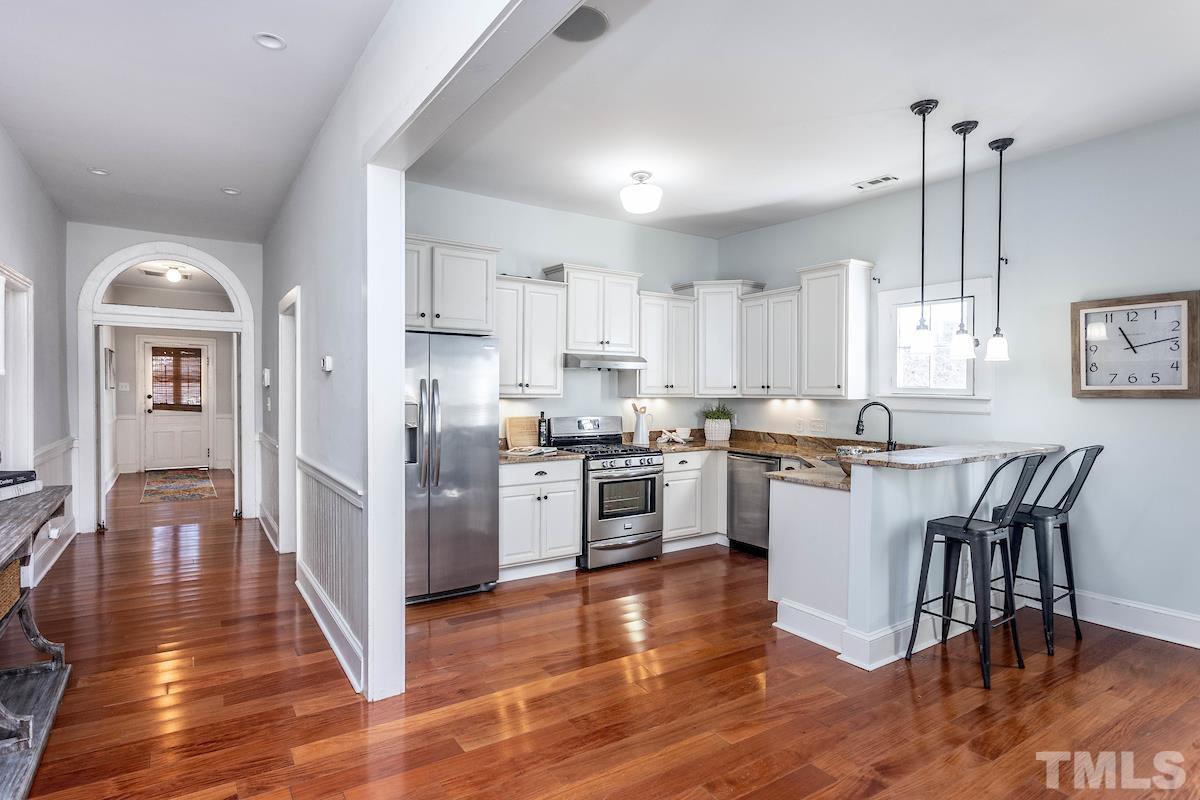 529 East Martin Street Raleigh, NC 27601 - Photo 10 of 29 a kitchen with stainless steel appliances granite countertop a refrigerator a stove top oven a sink dishwasher and white cabinets with wooden floor