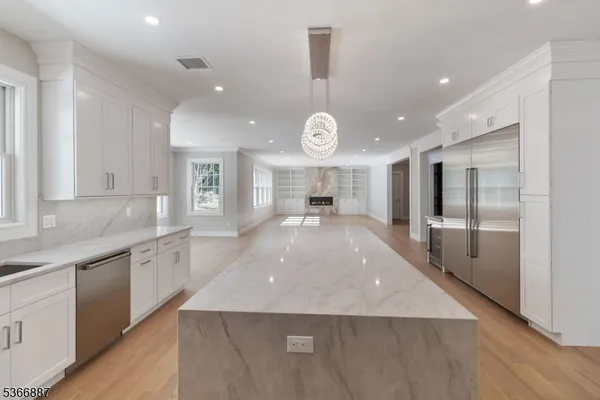 a large kitchen with stainless steel appliances a large counter top a sink a refrigerator and a granite counter tops