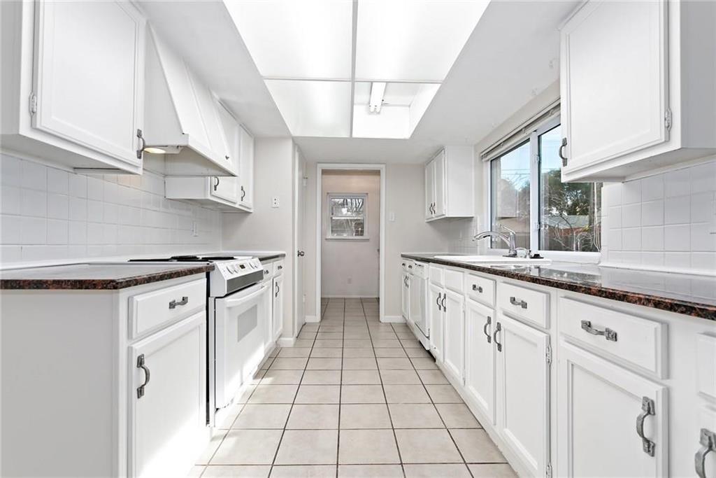 5000 Goodwin Drive Plano, TX 75023 - Photo 2 of 16 a large white kitchen with granite countertop a sink a window a counter space and stainless steel appliances