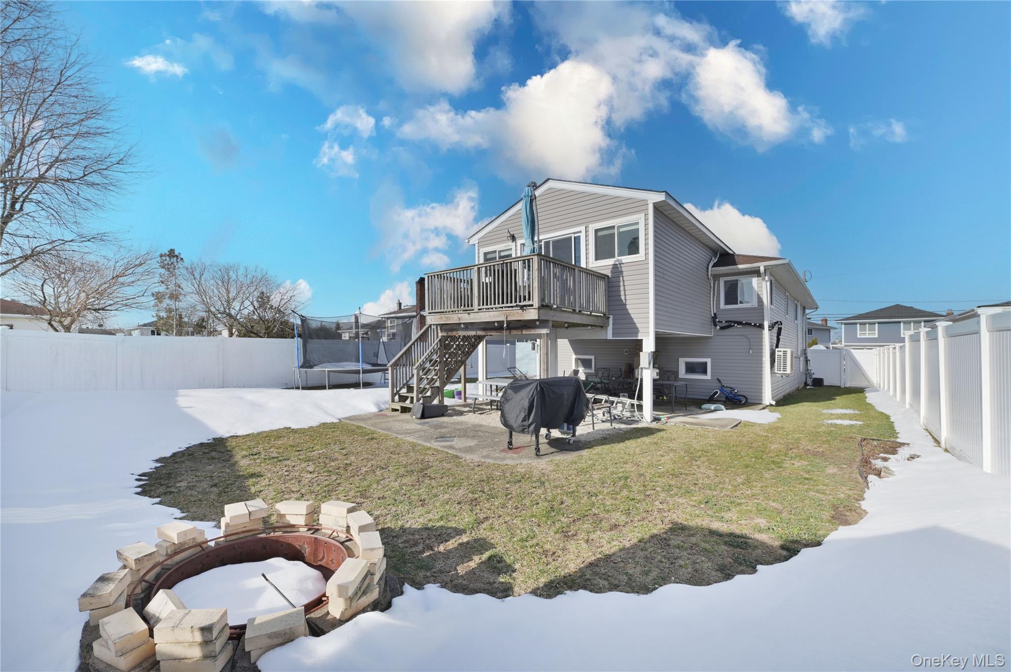 3485 Riverside Drive Oceanside, NY 11572 - Photo 29 of 30 Rear view of property featuring a patio, a fire pit, a fenced backyard, a wooden deck, and a trampoline