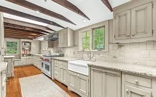 a kitchen with granite countertop a sink stainless steel appliances white cabinets and a window