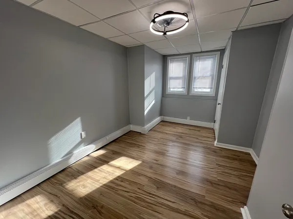 an empty room with wooden floor and windows
