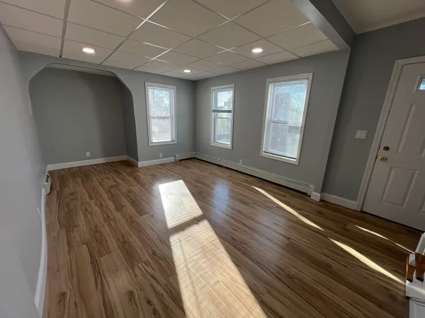 a view of an empty room with wooden floor and a window